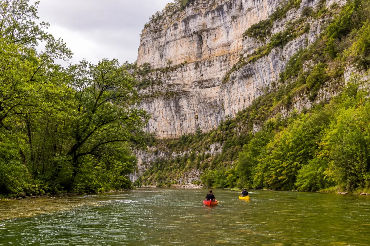 Deux canoës colorés sur la Loue au pied des falaises calcaires près d’Ornans